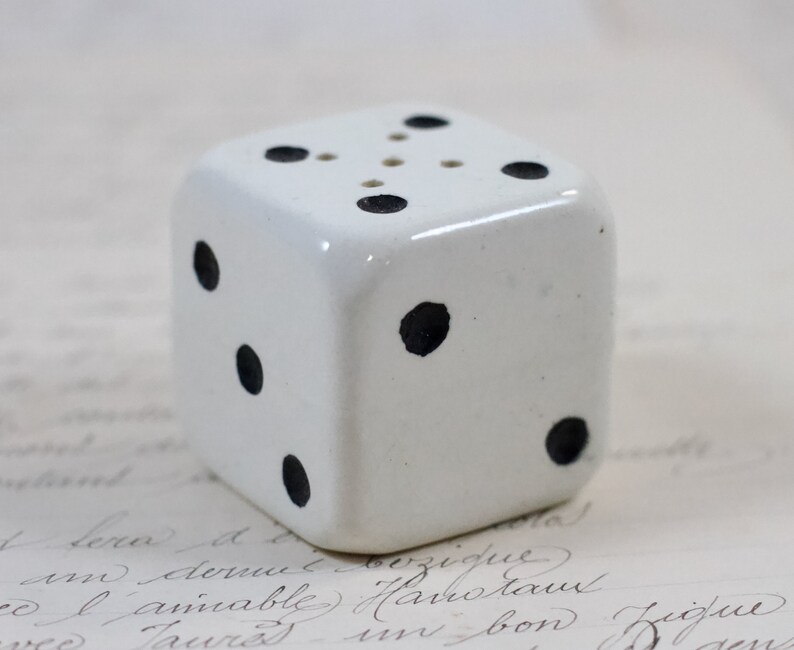 May include: White ceramic dice salt and pepper shaker with black dots. The dice has six sides and is a kitchen decor item.