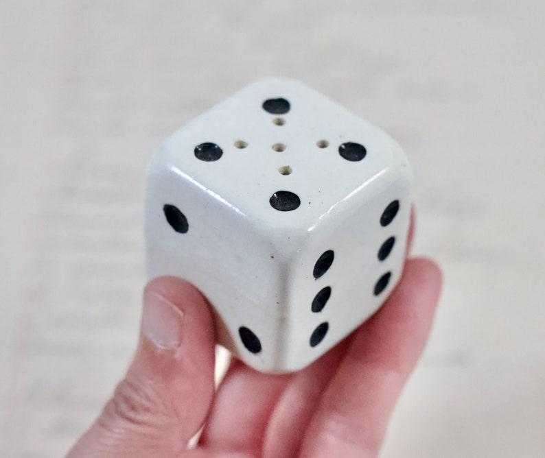 May include: White ceramic salt and pepper shaker shaped like a dice with black dots.