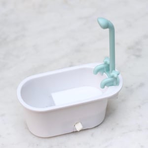 Op de afbeelding: Een wit plastic bad met een lichtblauwe douchekop en kraan. Het bad is ontworpen voor een poppenhuis of een miniatuur speelset.