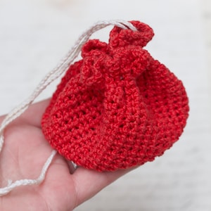 May include: A small red crocheted drawstring bag with a white cord.