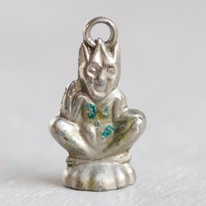 Op de afbeelding: Zilveren bedel van een zittende gargoyle met een puntige hoed en een ondeugende uitdrukking. De bedel heeft een lus aan de bovenkant om aan een ketting of armband te bevestigen.