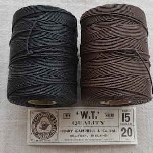 Könnte beinhalten: Zwei Spulen mit schwarzem und braunem Leinen-Schnürgarn, beschriftet mit "W.T. Quality" Henry Campbell & Co. Ltd. Belfast, Irland. Schnur 15, Geflochten 20.