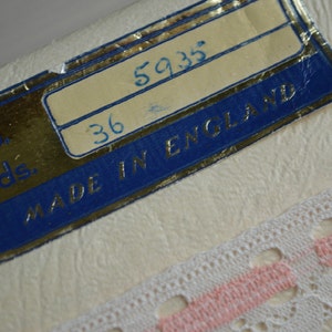May include: A white label with blue trim and gold lettering. The label reads "No. Yds. 36 5935 MADE IN ENGLAND".