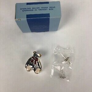 May include: Sterling silver teddy bear earrings in a blue trinket box. The earrings are silver with a red bow and a gold finish. The box has the text "Sterling Silver Teddy Bear Earrings in Trinket Box" printed on the top.