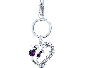 May include: Silver key chain with a heart-shaped charm featuring two purple crystal thistle flowers.