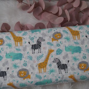 Könnte beinhalten: Weißer Stoff mit einem sich wiederholenden Muster von Dschungeltieren, darunter Giraffen, Zebras, Löwen und Nashörner. Die Tiere sind im Cartoon-Stil mit leuchtenden Farben auf weißem Hintergrund illustriert.