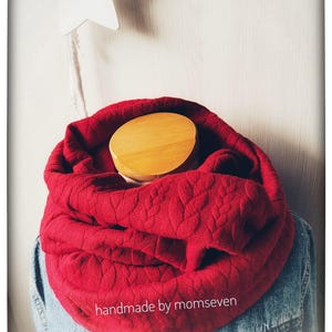 Könnte beinhalten: Ein gesteppter, roter Loop-Schal mit Blättermuster, präsentiert auf einer Schaufensterpuppe. Der Schal ist um den Hals gewickelt und wird mit einer Jeansjacke kombiniert. Der Text "handmade by momseven" ist sichtbar.