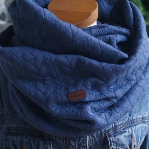 Könnte beinhalten: Ein blauer Infinity-Schal mit einem strukturierten Blumenmuster. Der Schal hat ein braunes Leder-Etikett mit dem Text "Made in Italy" darauf.