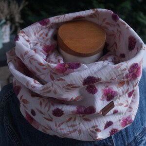 Könnte beinhalten: Weißer Baumwoll-Halswärmer mit einem Blumendruck mit rosa und violetten Blumen, braunen Blättern und dunkelvioletten Beeren. Der Halswärmer befindet sich auf einer Puppe.