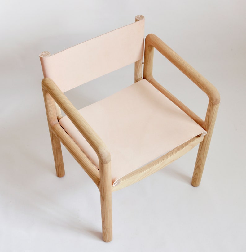May include: A light wood chair with a light pink leather seat and back.