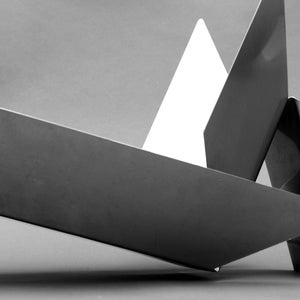 Può includere: Una scultura geometrica composta da tre pezzi di metallo. La scultura è realizzata in metallo grigio chiaro e metallo grigio scuro. La scultura è astratta e moderna.