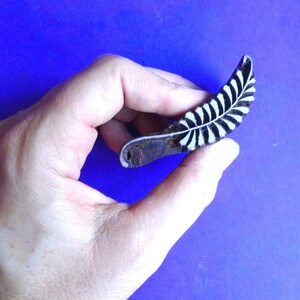 May include: A wooden block printing stamp featuring a black and white leaf design. The stamp is carved with a detailed leaf pattern and is ready to be used for creating unique prints.