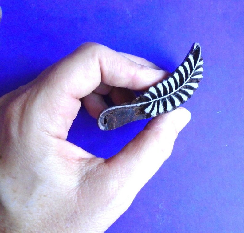 May include: A wooden block printing stamp featuring a black and white leaf design. The stamp is carved with a detailed leaf pattern and is ready to be used for creating unique prints.