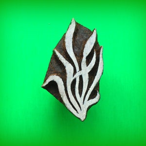 May include: A wooden block printing stamp with a carved design of stylised leaves. The stamp is brown with white carved details.