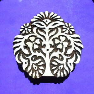 May include: A white wooden block printing stamp with a detailed floral design. The design features a tree with leaves and flowers, all carved into the wood. The stamp is perfect for creating unique patterns on fabric or paper.
