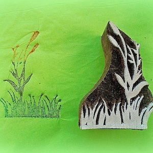 May include: A wooden block carving of a plant with leaves and stems. The carving is used to create a print on fabric or paper.