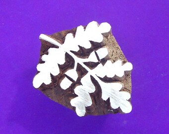 May include: A wooden block printing stamp featuring a white leaf design. The stamp is carved with a detailed leaf pattern and is ready to be used for creating unique prints.