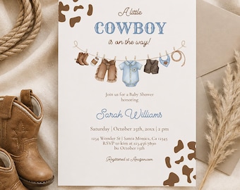 May include: A white baby shower invitation card featuring brown cow print corners and a clothesline illustration with miniature cowboy boots, chaps, a blue onesie, a vest, a bandana, and a lasso. The text reads A little COWBOY is on the way!