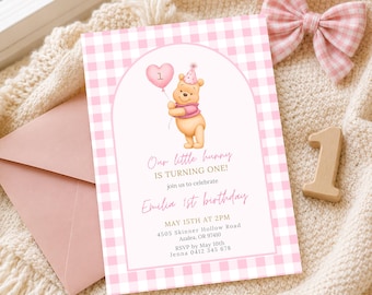 May include: A rectangular birthday invitation card with a pink and white gingham border. The center features a cartoon bear wearing a party hat and holding a heart-shaped balloon. Text reads: Our little hunny IS TURNING ONE! EMILIA 1st BIRTHDAY MAY 15TH AT 2PM.