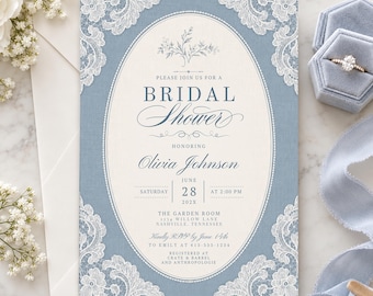 May include: A dusty blue bridal shower invitation card featuring a central cream oval, white lace corner accents, and dark blue text reading Please Join Us For A Bridal Shower Honoring Olivia Johnson, Saturday June 28 202X at 2:00 PM.