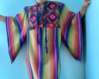 May include: A long, colorful striped dress with a geometric embroidered neckline. The dress has a loose fit and long sleeves.