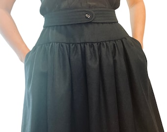 May include: A black skirt with a high waist and a gathered, flowing design. The skirt has a belt with a single button closure.