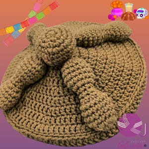 May include: A brown crocheted hat with a large bow on the side. The hat is made with a chunky yarn and has a textured surface.