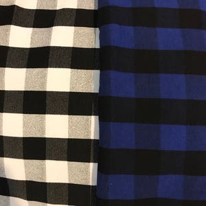 May include: Close-up of two fabrics with a checkered pattern. One fabric is black and white, the other is black and blue. The checkered pattern is made up of large squares.