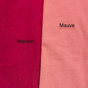 May include: Two fabric swatches, one maroon and one mauve, are displayed side by side. The word "Maroon" is printed below the maroon swatch, and the word "Mauve" is printed below the mauve swatch. The fabrics appear to be a soft knit.