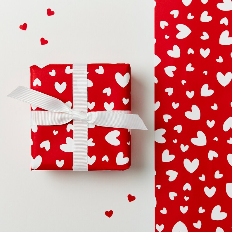 May include: A red gift box with a white ribbon and white hearts on a red background. The box is surrounded by small red hearts.