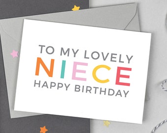 May include: A white card with the text "To my lovely niece Happy Birthday" in grey lettering. The word "niece" is spelled out in colorful letters: orange, teal, pink, yellow, and red.