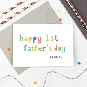 May include: A white card with the text "happy 1st father's day" in colorful letters. The date "18.06.17" is printed below the text.