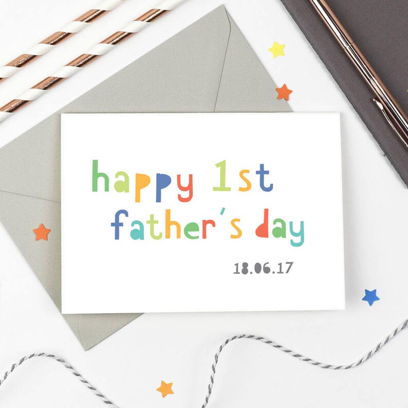 May include: A white card with the text "happy 1st father's day" in colorful letters. The date "18.06.17" is printed below the text.