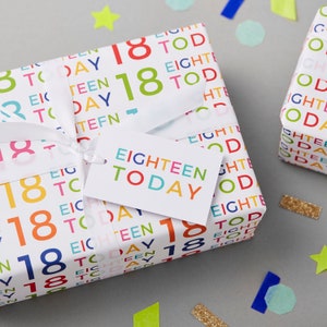 May include: A white gift box wrapped in colorful paper with the words "18 Today" and "Eighteen Today" printed on it. A white gift tag with the words "Eighteen Today" is attached to the box.