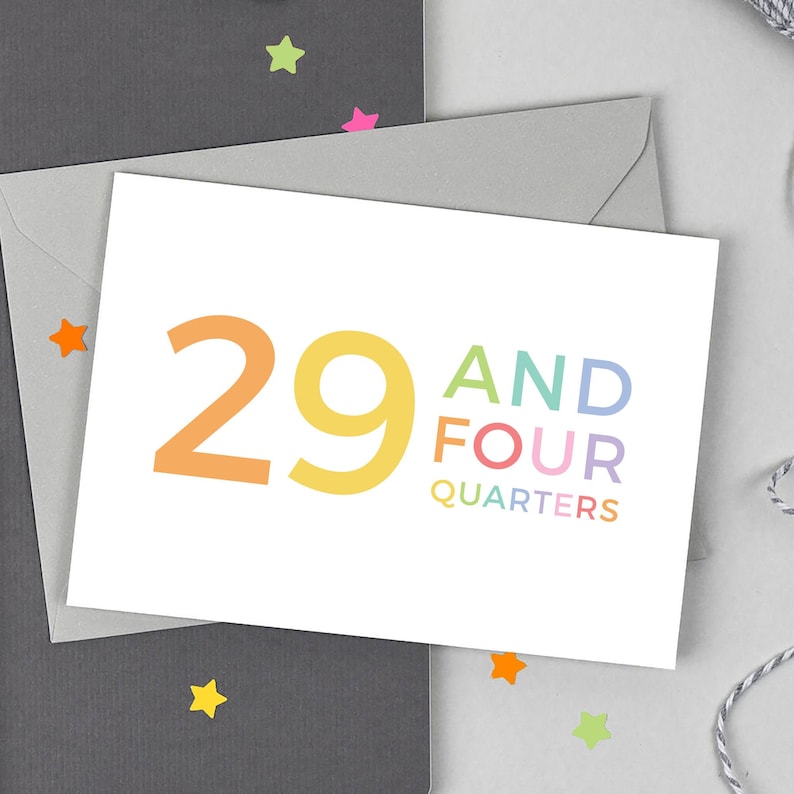 May include: A white card with the text "29 and four quarters" in rainbow colors. The number 29 is large and the rest of the text is smaller.