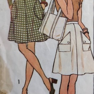 May include: Two women's fashion illustrations. The woman on the left is wearing a green long-sleeved shirt and a plaid skirt. The woman on the right is wearing a brown short-sleeved shirt and a white skirt with large pockets. Both women are wearing brown shoes.