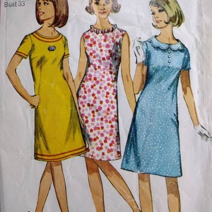 May include: A vintage sewing pattern for a dress with three different styles. The pattern is for a Jr. Petite size 11 1/2p, bust 33. The dress styles include a yellow dress with a red trim, a floral print dress, and a blue polka dot dress.