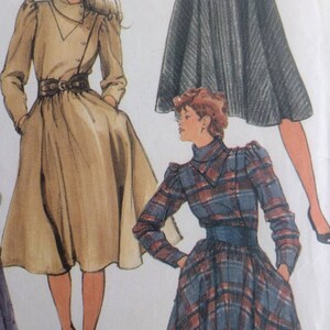 May include: Two women's dresses with long sleeves and a fitted waist. The dress on the left is a light brown colour with a belt. The dress on the right is a blue and red plaid pattern.