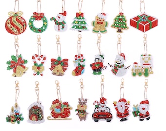 May include: Set of 20 Christmas-themed diamond painting keychains. The keychains feature various holiday designs, including ornaments, candy canes, reindeer, Santa Claus, and snowmen. Each keychain is made with colorful rhinestones and has a gold-colored metal ring.