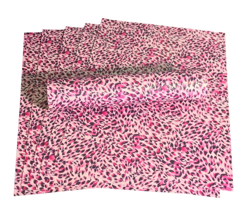 May include: A stack of pink and black leopard print craft paper. The paper is rolled up and has a shiny, glittery finish.