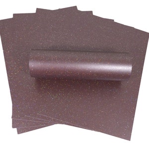 May include: A collection of dark mauve glitter paper sheets, with a rolled-up sheet on top. The paper has a speckled, iridescent effect. Suitable for crafts and scrapbooking projects.