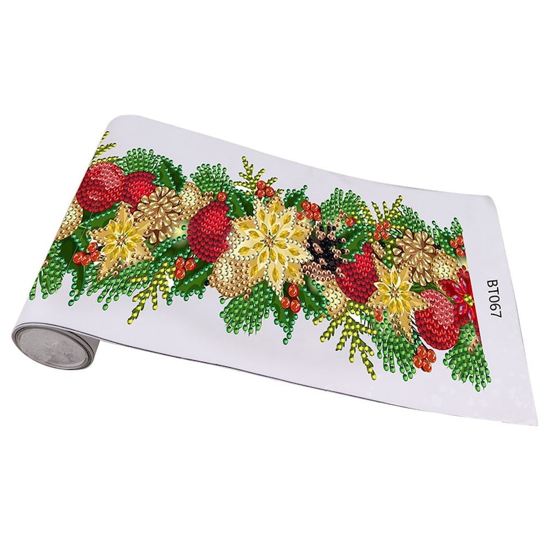 May include: A white canvas with a Christmas-themed design featuring red and gold ornaments, green leaves, and pine cones. The design is made of rhinestones and is rolled up for storage. The text "BT067" is printed on the canvas.