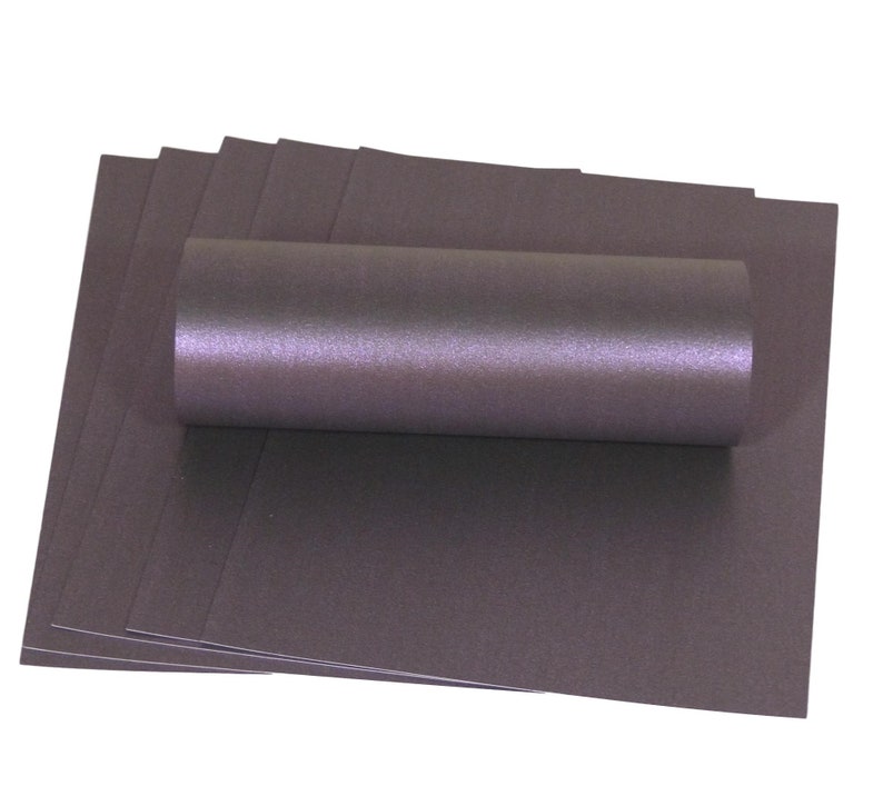 May include: A stack of A4 sheets of metallic purple cardstock. The cardstock is rolled up and has a shimmery finish.