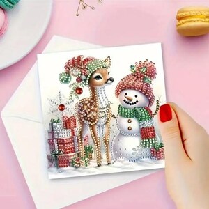 May include: A Christmas card featuring a cartoon deer and snowman with a red, green, and white color scheme. The deer is wearing a red and green hat and the snowman is wearing a red and green scarf. The card is decorated with presents and snowflakes.