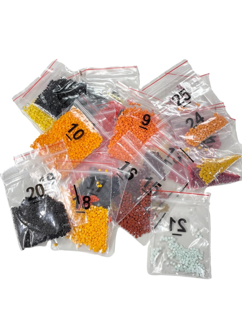 May include: Assortment of small plastic bags filled with colorful beads, each bag labeled with a number from 10 to 25. The beads are likely for a diamond painting project.