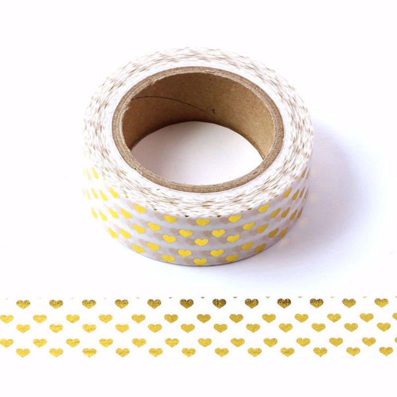 May include: A roll of white washi tape with a gold heart pattern. The tape is on a white background.