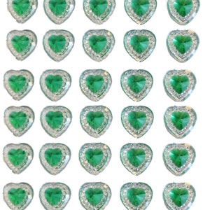 May include: A collection of heart-shaped embellishments. Each heart features a vibrant green center stone surrounded by a border of clear, sparkling rhinestones. The hearts are arranged in a grid pattern against a white background.