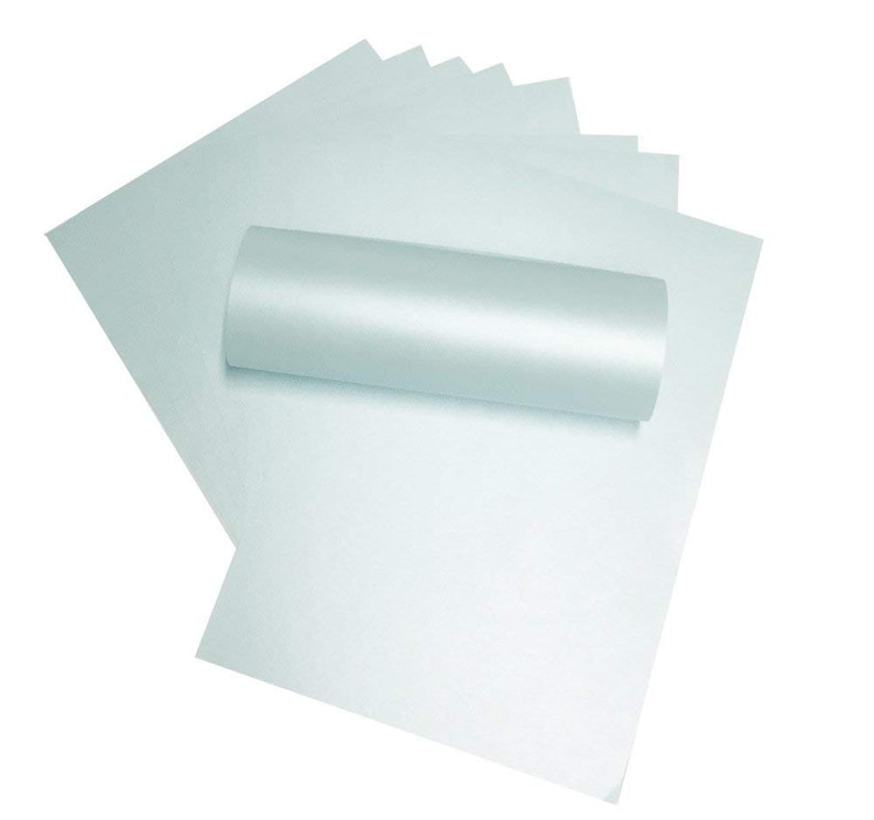 May include: A roll of light blue metallic paper. The paper is rolled up and the ends are visible. The paper is smooth and shiny.