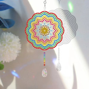 May include: A colorful rainbow mandala wind chime with a crystal drop. The mandala is made of iridescent beads and has a starburst design in the center. The wind chime is suspended from a silver hook.