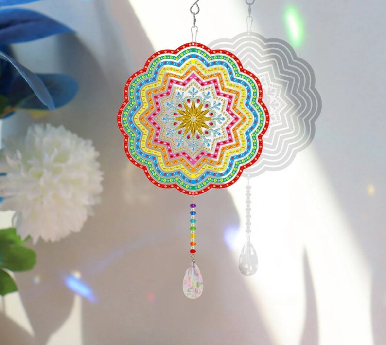May include: A colorful rainbow mandala wind chime with a crystal drop. The mandala is made of iridescent beads and has a starburst design in the center. The wind chime is suspended from a silver hook.